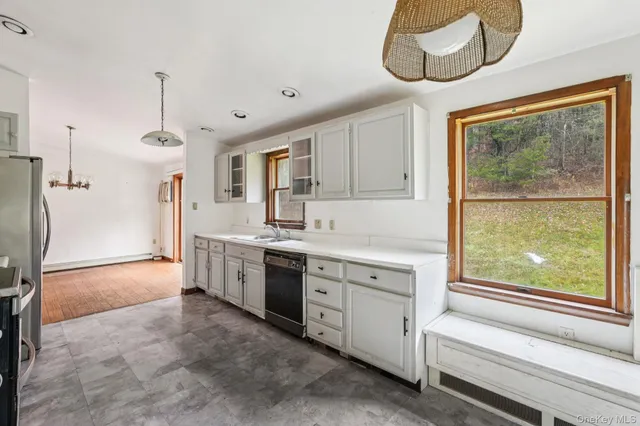 a kitchen with white cabinets and window