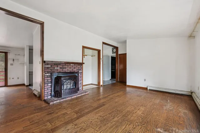 an empty room with wooden floor a fireplace and windows