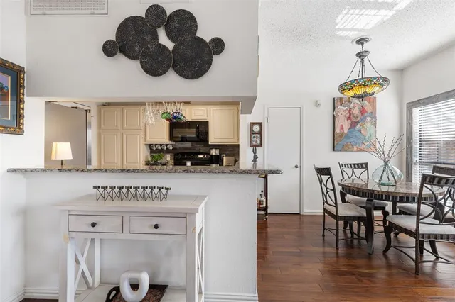 a kitchen with stainless steel appliances granite countertop a table chairs in it and wooden floors