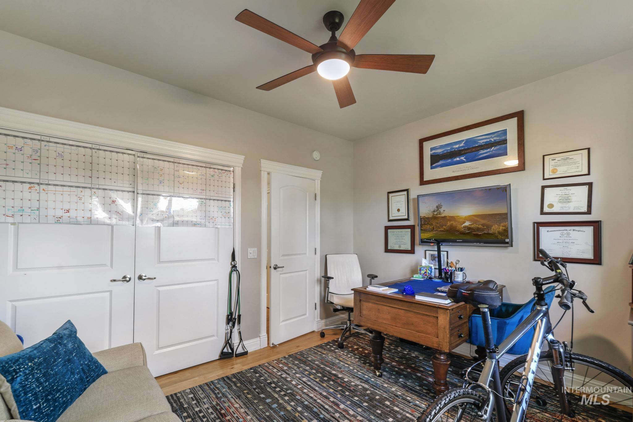 100 Olympic Road Jerome, ID 83338 - Photo 24 of 50 Room featuring wood-finish flooring, a ceiling fan with integrated lighting, a wall-mounted television, and white panel doors with decorative trim