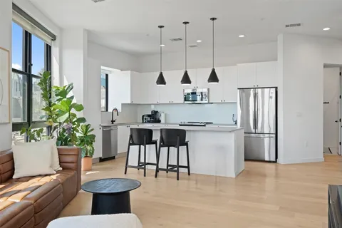 a kitchen with stainless steel appliances kitchen island granite countertop a refrigerator a stove and a wooden floors