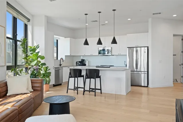 a kitchen with stainless steel appliances kitchen island granite countertop a refrigerator a stove and a wooden floors