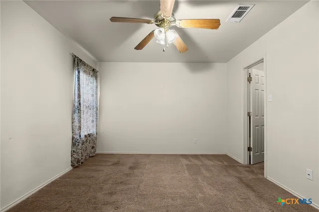 an empty room with windows and fan