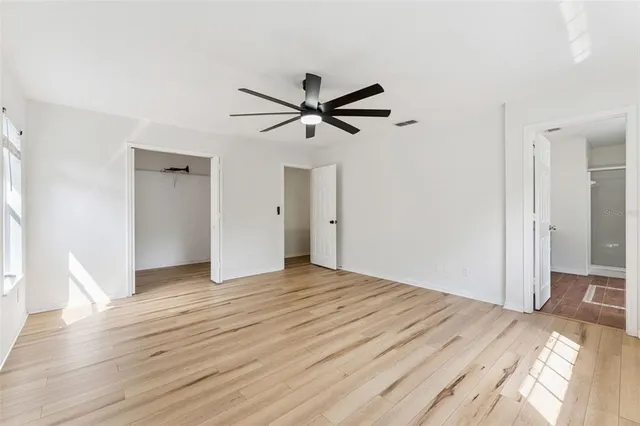 a view of empty room with wooden floor and ceiling fan