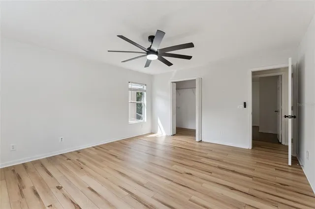 a view of a livingroom with a chandelier fan and wooden floor