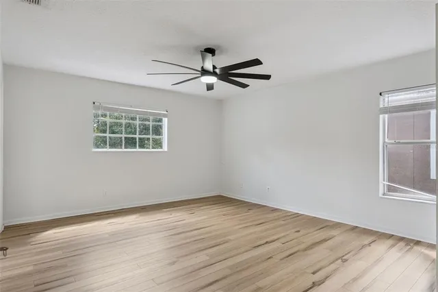 a view of empty room with wooden floor and fan