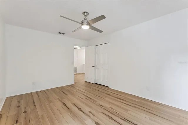 an empty room with wooden floor and a ceiling fan