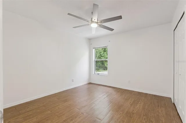 an empty room with a window and a ceiling fan