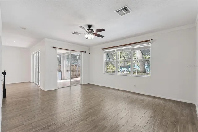 a view of an empty room with a window and wooden floor