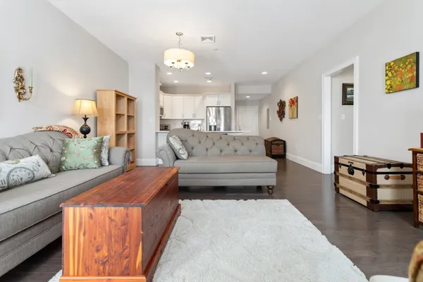 a living room with furniture and a dining table with wooden floor