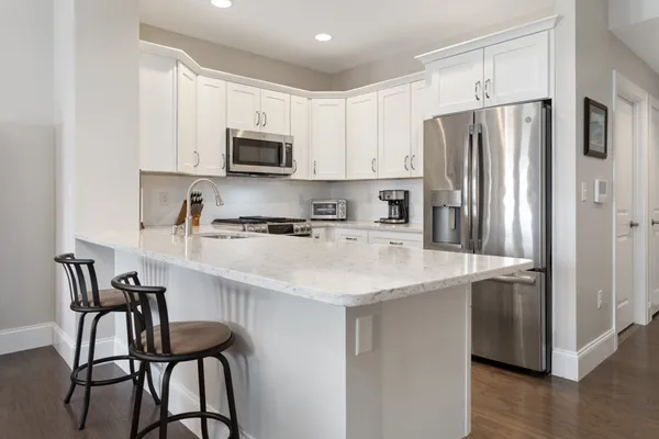 a kitchen with stainless steel appliances granite countertop a refrigerator a sink a stove a dining table and chairs