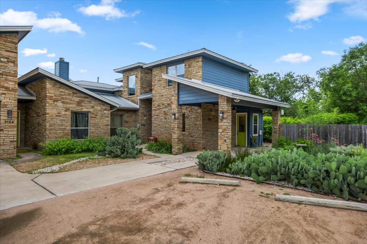913 Stobaugh Street, Unit B Austin, TX 78757 - Photo 2 of 40 A striking exterior featuring stacked stone and bold blue siding with a verdant, low-maintenance landscape.
