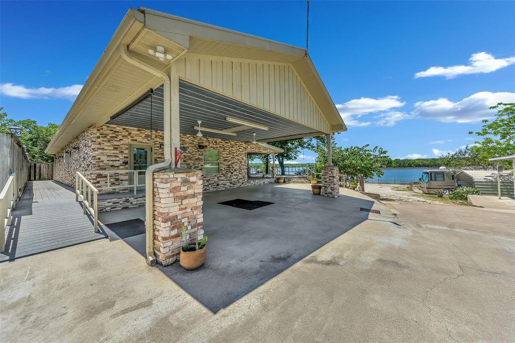 566 Selma Park Road Bowie, TX 76230 - Photo 19 of 40 Exterior featuring stacked stone accents, covered outdoor area, concrete surfacing, and water frontage