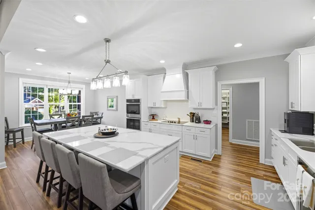 a large kitchen with sink a refrigerator and wooden floor