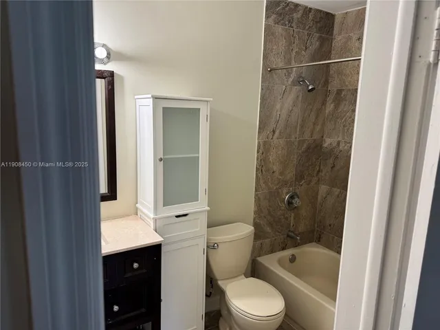 a bathroom with a bathtub shower sink vanity and toilet
