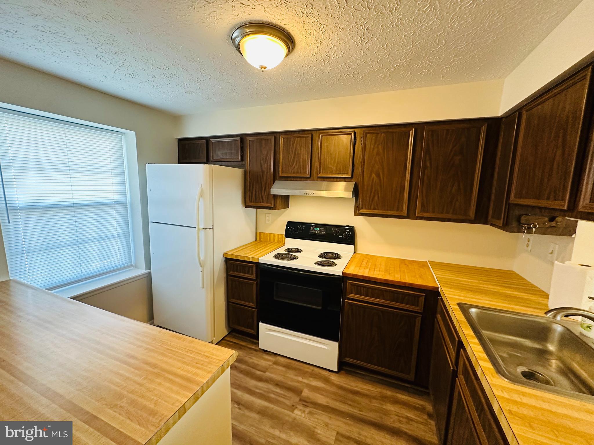 6820 Farmbrook Court Frederick, MD 21703 - Photo 4 of 17 a kitchen with wooden cabinets and a stove top oven