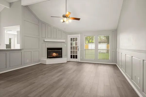 a view of an empty room with wooden floor fireplace and a window