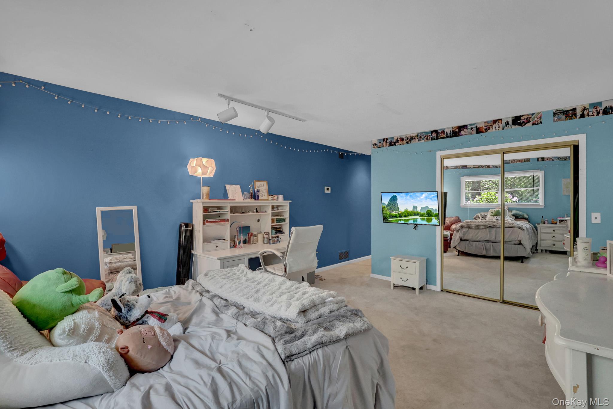 15 Stillwater Road Nissequogue, NY 11780 - Photo 20 of 43 2nd primary Wall-to-wall carpeting throughout this expansive room, featuring a built-in desk unit with shelving, mirrored closet doors, and recessed track lighting