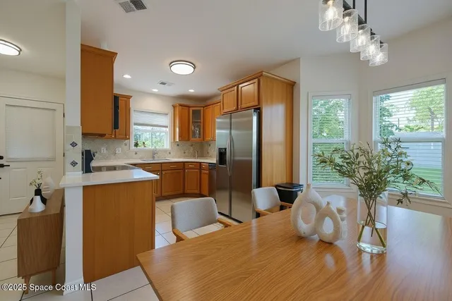 a kitchen with granite countertop a refrigerator a stove a sink dishwasher and a dining table with wooden floor