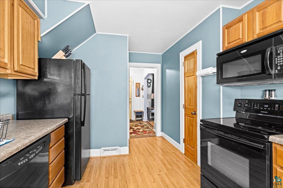 4316 West 6th Street Duluth, MN 55807 - Photo 23 of 38 Kitchen with black appliances, light wood-type flooring, crown molding, wood finish cabinetry, and light countertops