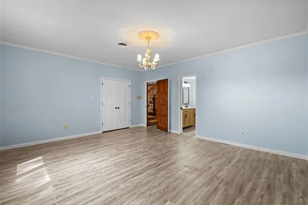 an empty room with wooden floor chandelier and windows