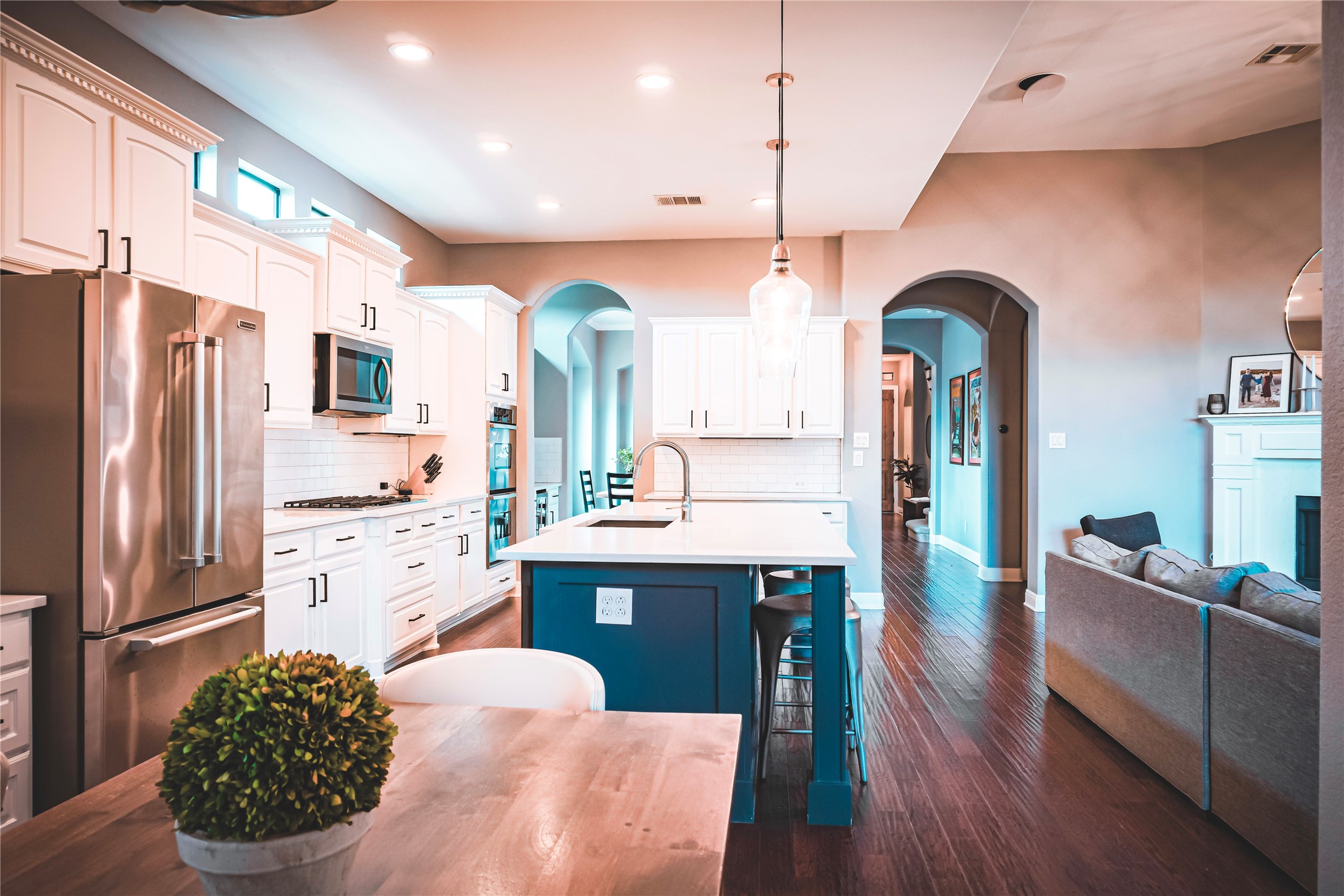 102 Indigo Run Cove Austin, TX 78738 - Photo 2 of 24 Dual tone kitchen featuring stainless steel appliances, a breakfast bar area, a kitchen island with sink, dark wood-style floors, and hanging light fixtures