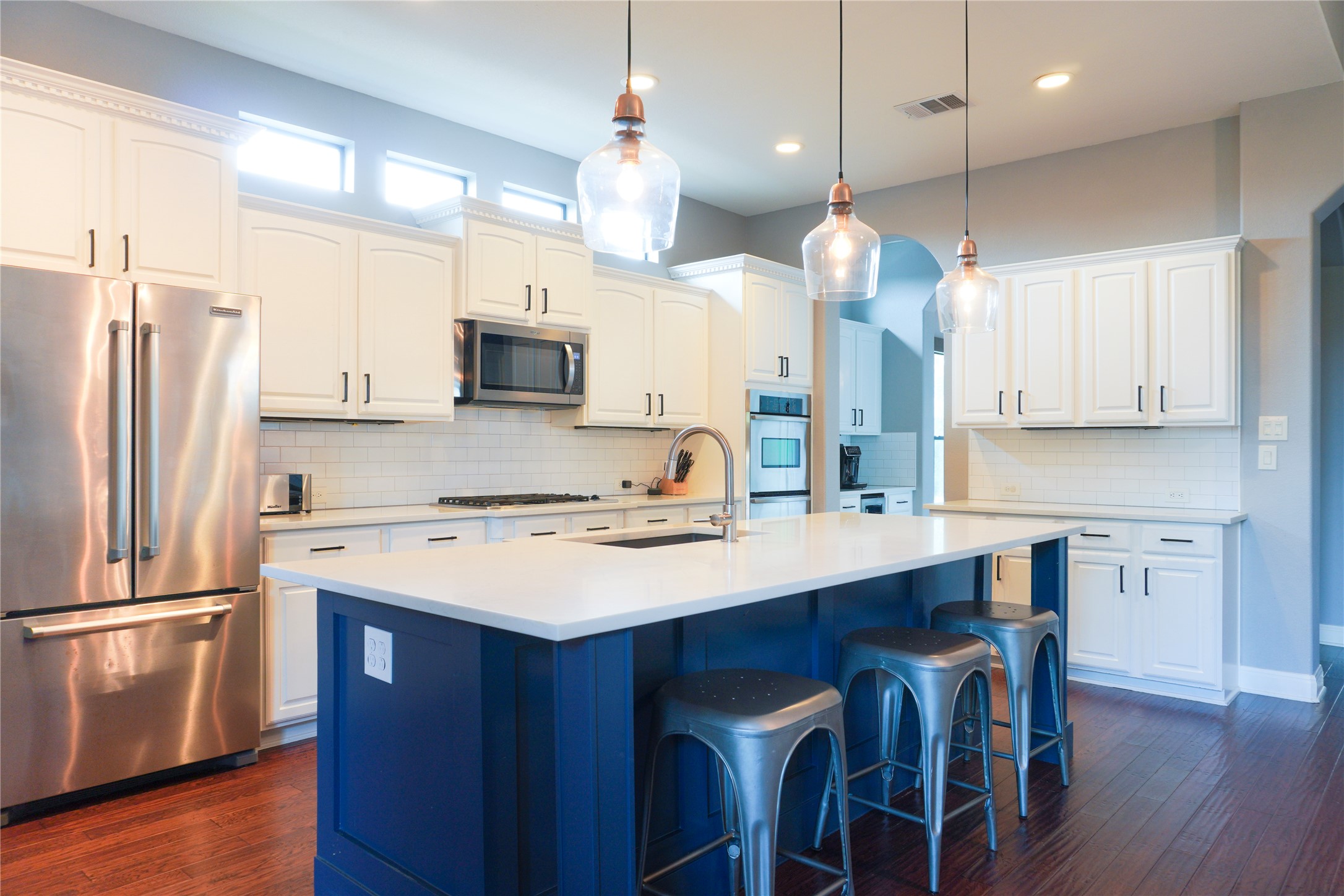 102 Indigo Run Cove Austin, TX 78738 - Photo 3 of 24 Kitchen featuring stainless steel appliances, a kitchen island with sink, a breakfast bar, dark wood-style floors, and decorative light fixtures