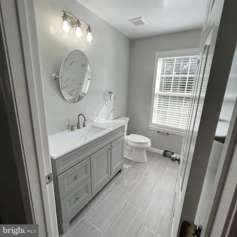a bathroom with a double vanity sink toilet mirror and window