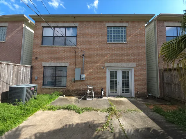 a view of a brick house with plants and large tree