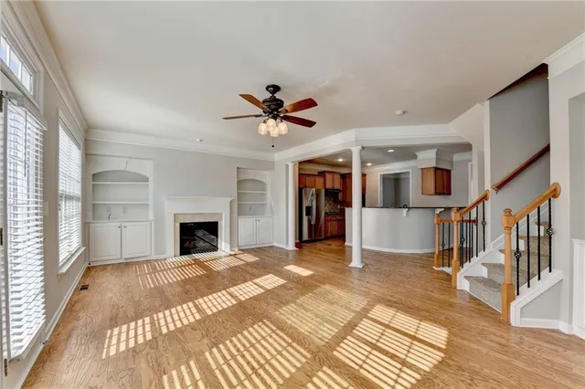 a view of a livingroom with a fireplace a ceiling fan and wooden floor