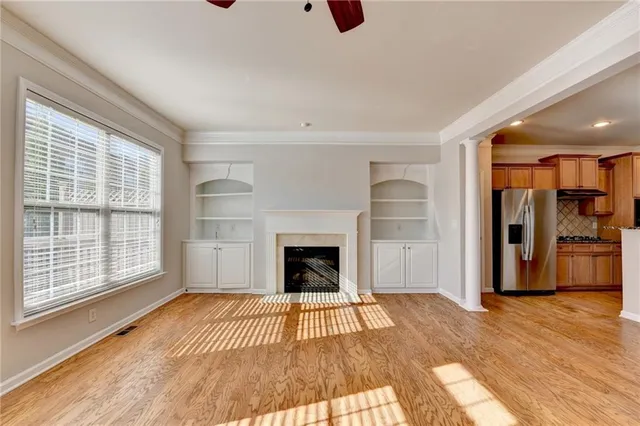 a view of an empty room with wooden floor fireplace and a window