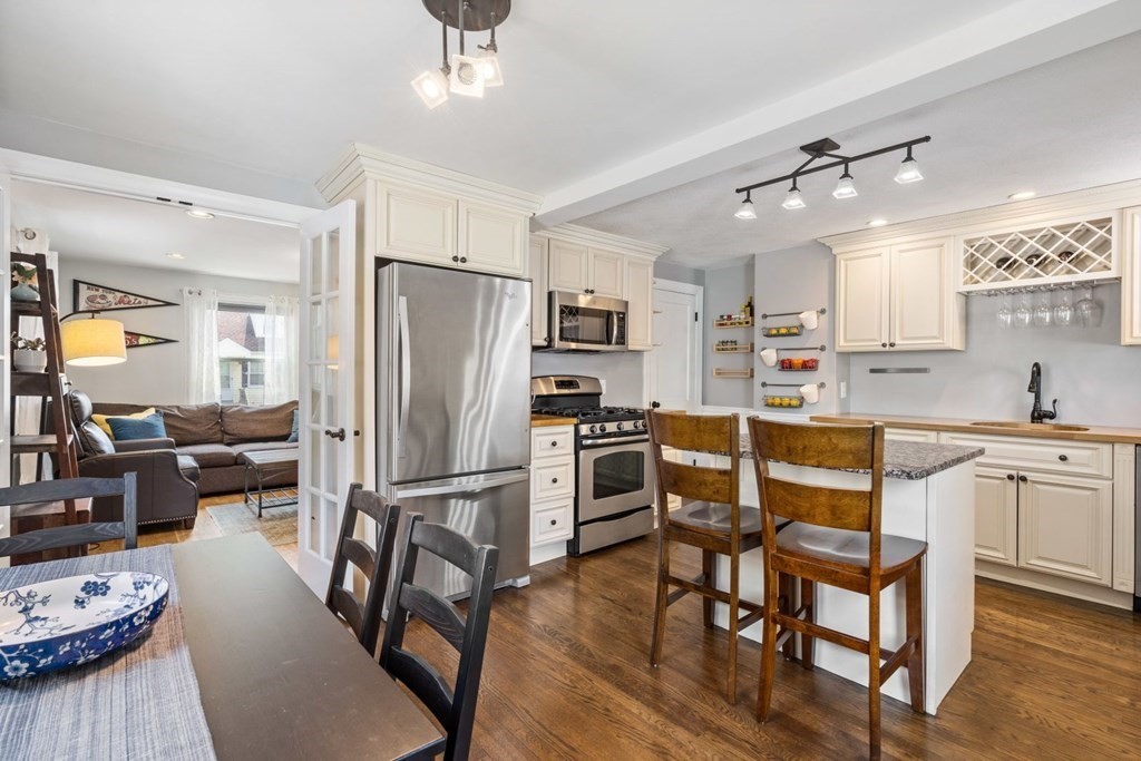 33 Bromfield Street, Unit 33 Watertown, MA 02472 - Photo 5 of 21 a kitchen with stainless steel appliances granite countertop a refrigerator a stove a sink a dining table and chairs with wooden floor
