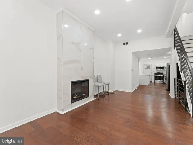 a view of a livingroom with wooden floor a fireplace and entryway