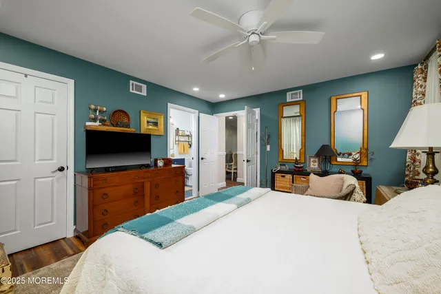a bedroom with a large bed and a flat tv screen on dresser
