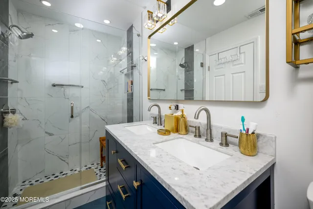 a bathroom with a granite countertop sink a mirror and shower