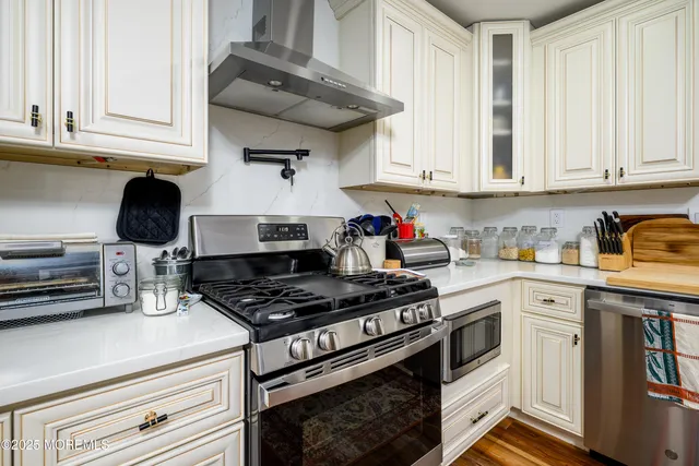 a kitchen with stainless steel appliances granite countertop a stove and a white cabinets