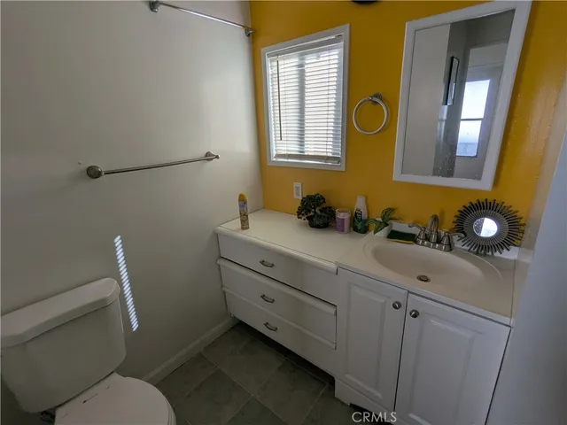 a bathroom with a granite countertop toilet sink and mirror
