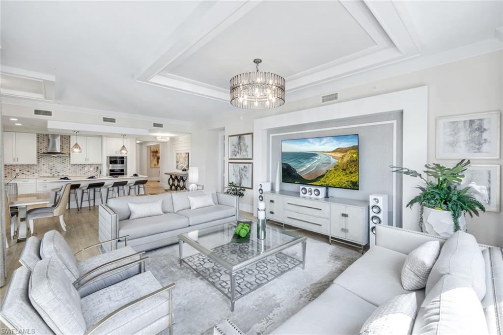 a living room with furniture a chandelier and a flat screen tv