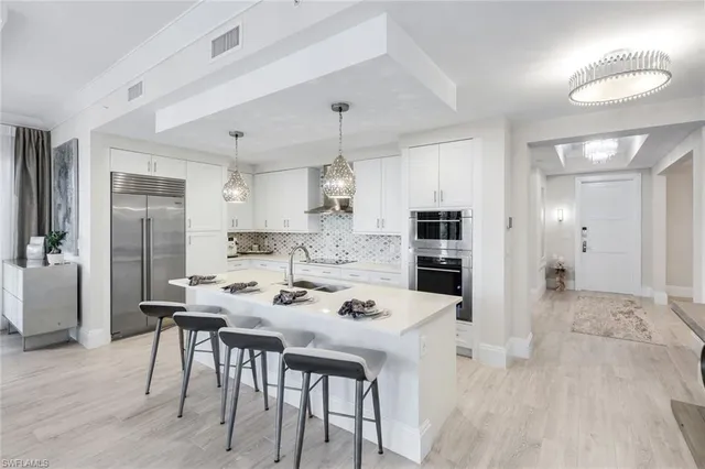 a kitchen with stainless steel appliances kitchen island granite countertop a dining table chairs and refrigerator