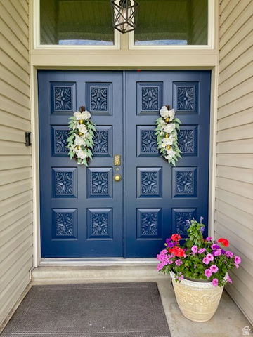 2444 Quail Run Drive Sandy, UT 84093 - Photo 2 of 23 Double entry doors in a deep blue finish, featuring intricate carved panels and brass hardware