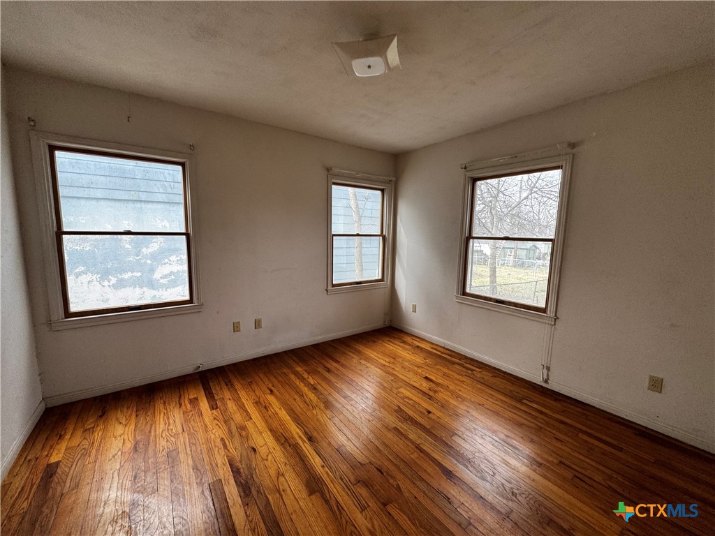 1010 South 17th Street Temple, TX 76504 - Photo 18 of 30 an empty room with wooden floor and windows
