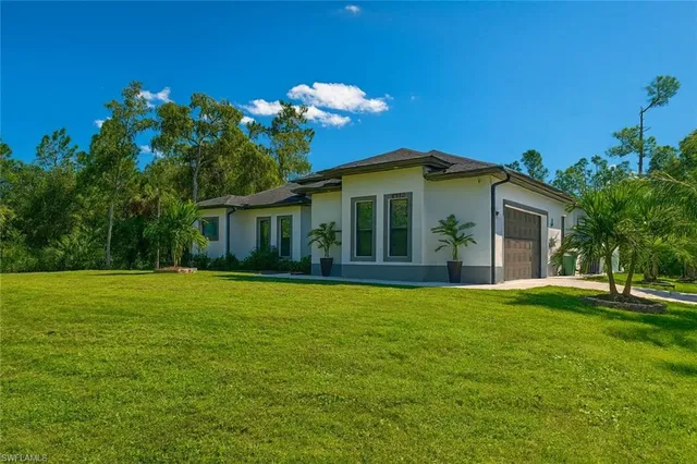 a front view of a house with a yard and palm trees