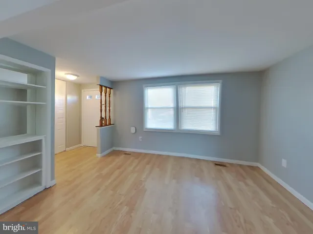 a view of an empty room with a window and wooden floor