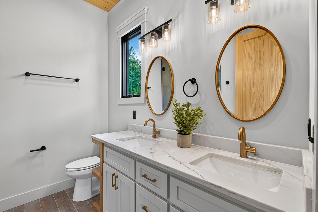 44 Staurolite Mountain Road Blue Ridge, GA 30513 - Photo 70 of 108 a bathroom with a granite countertop toilet a sink and a mirror