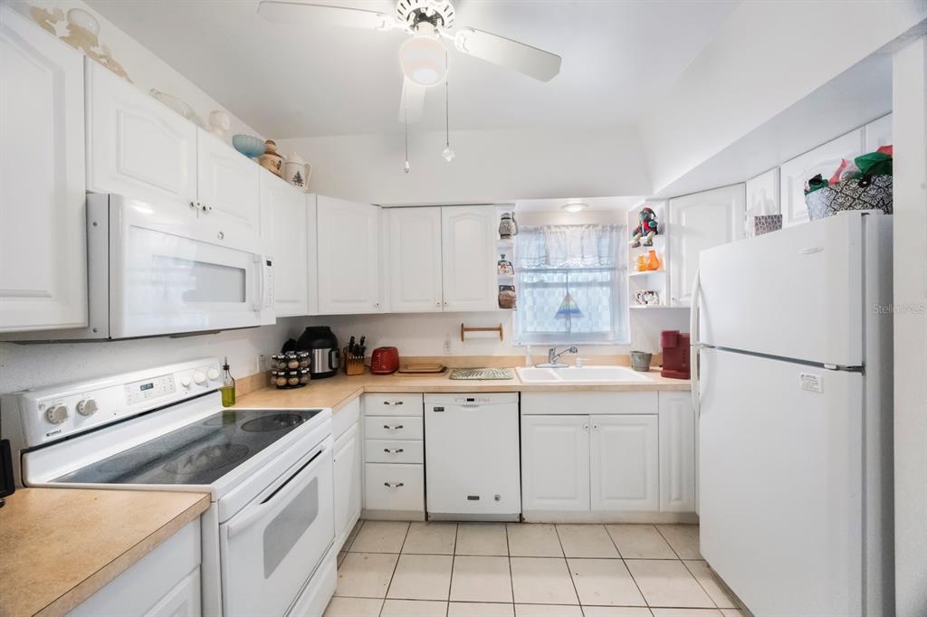 9945 47th Avenue North, Unit 203 St. Petersburg, FL 33708 - Photo 7 of 29 a kitchen with a white cabinets and white appliances