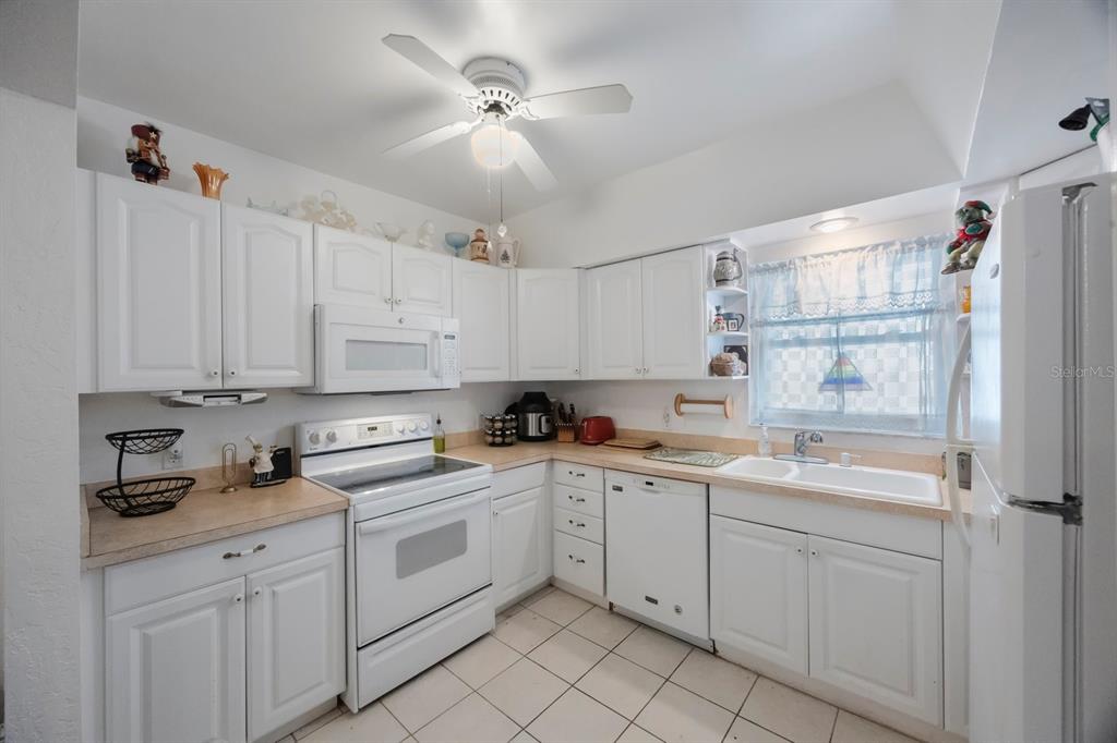 9945 47th Avenue North, Unit 203 St. Petersburg, FL 33708 - Photo 8 of 29 a kitchen with white cabinets appliances and a sink