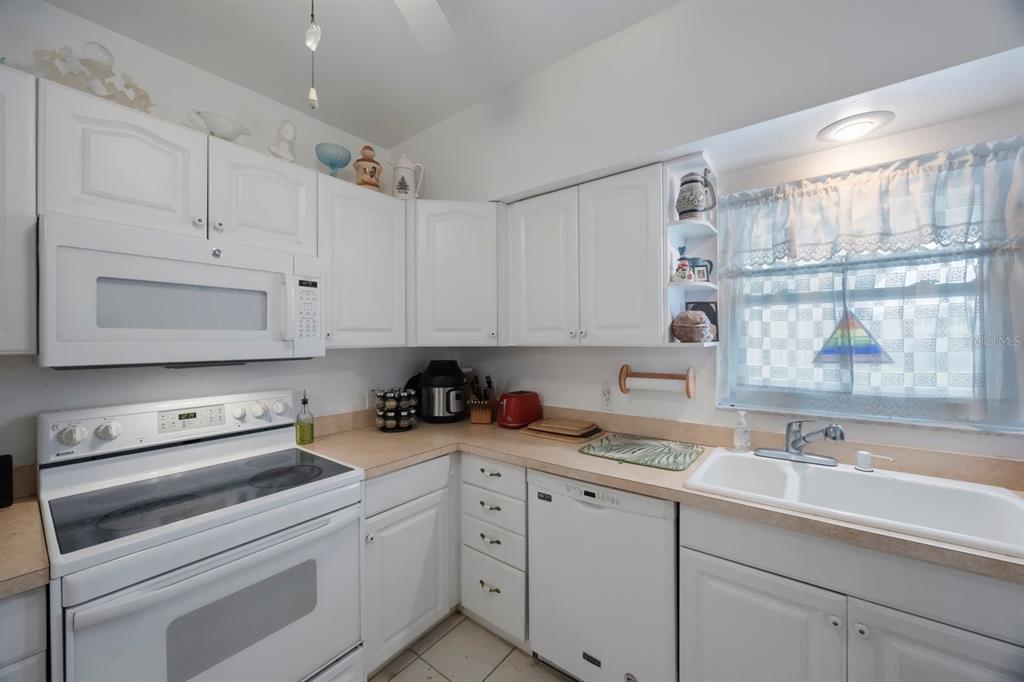 9945 47th Avenue North, Unit 203 St. Petersburg, FL 33708 - Photo 9 of 29 a kitchen with cabinets appliances a sink and a counter top space