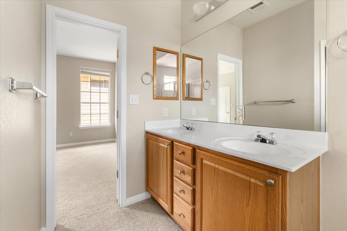 11000 Anderson Mill Road, Unit 11 Austin, TX 78750 - Photo 15 of 34 Double vanities and a well-lit mirror create a functional and pleasant primary bathroom.