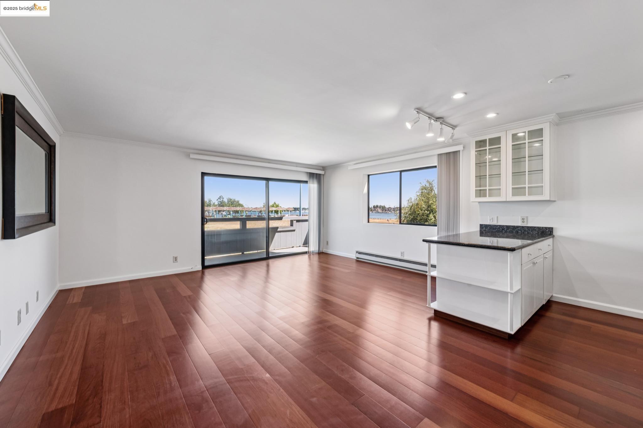 1 Embarcadero, Unit 161 Oakland, CA 94607 - Photo 22 of 31 Unfurnished living room with a baseboard heating unit, dark wood-style floors, crown molding, and track lighting