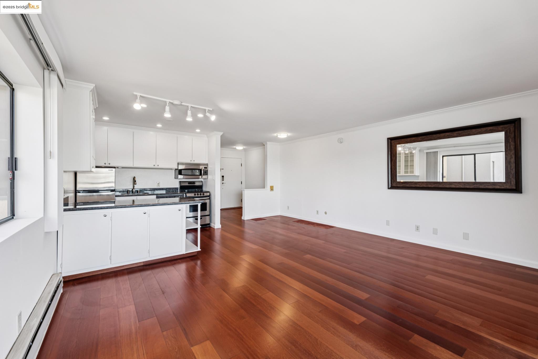 1 Embarcadero, Unit 161 Oakland, CA 94607 - Photo 31 of 31 Kitchen featuring white cabinetry, dark countertops, a baseboard radiator, open floor plan, and ornamental molding